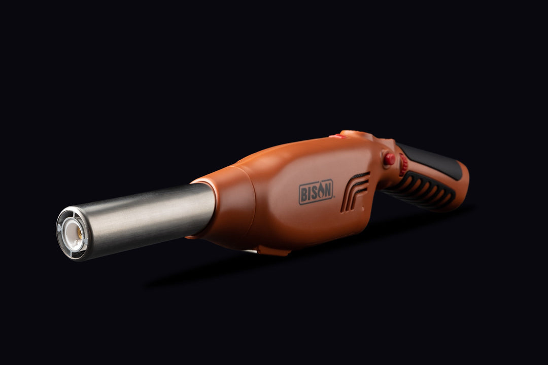 A Bison brand Airlighter with a metallic silver nozzle and an orange body with a black textured grip, shown against a solid black background.