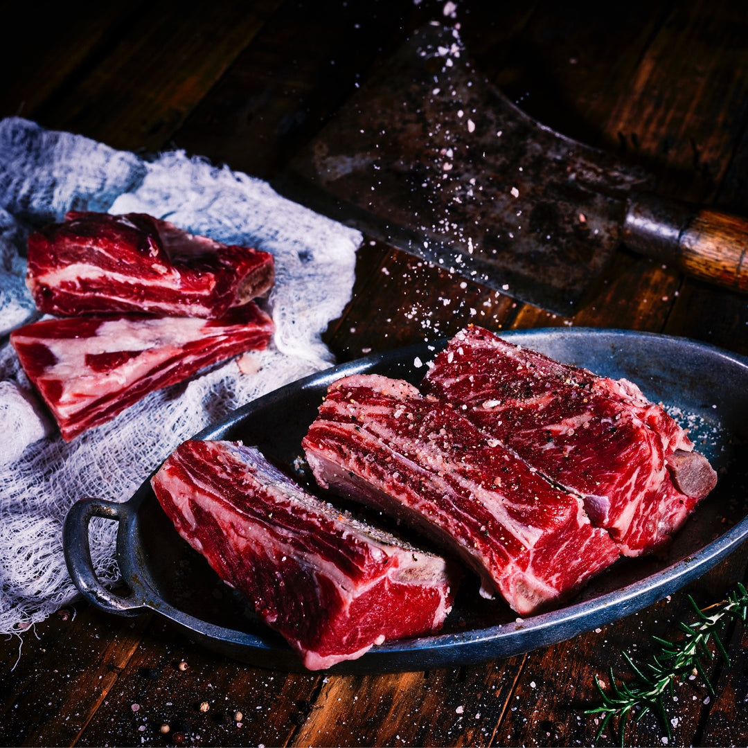 Image of raw meat on a plate being sprinkled with salt