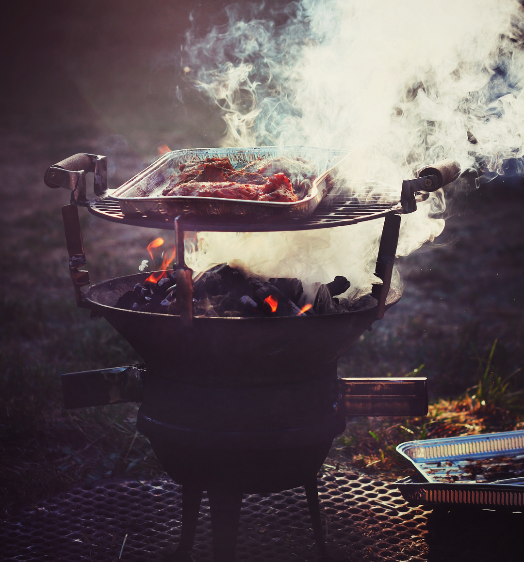Image of meat being smoked over coals
