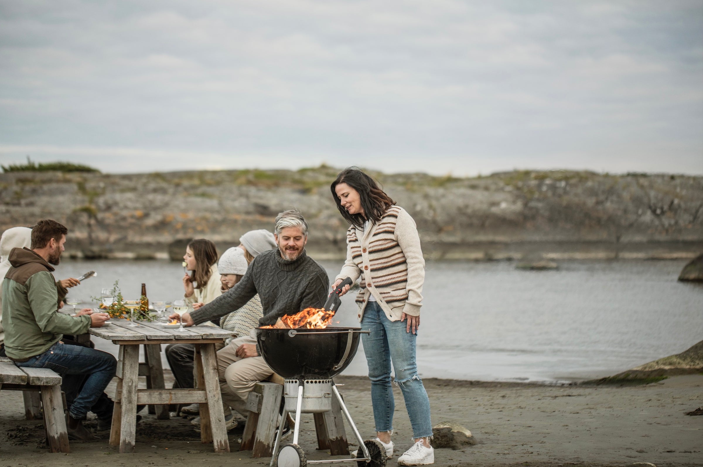 Woman using Airlighter on a Weber grill with friends