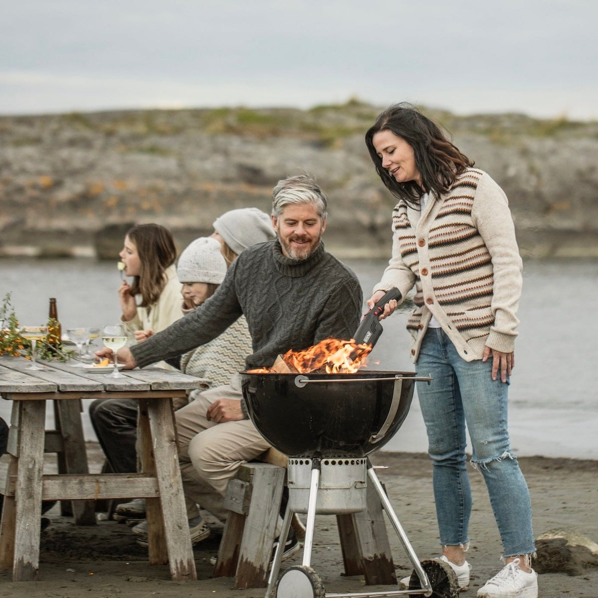 Woman using Airlighter on a Weber grill with friends