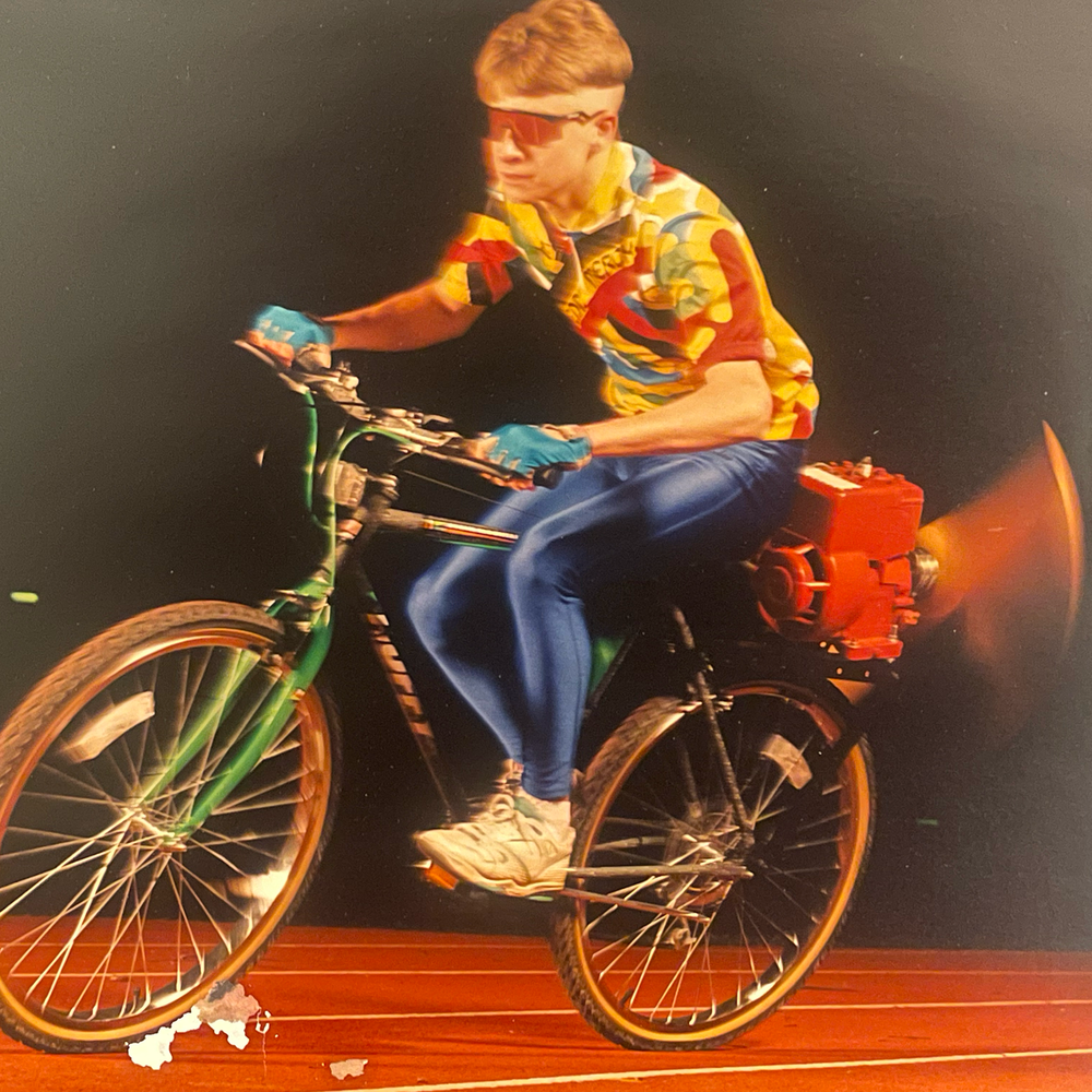 StJohn riding an early propeller-powered bicycle invention